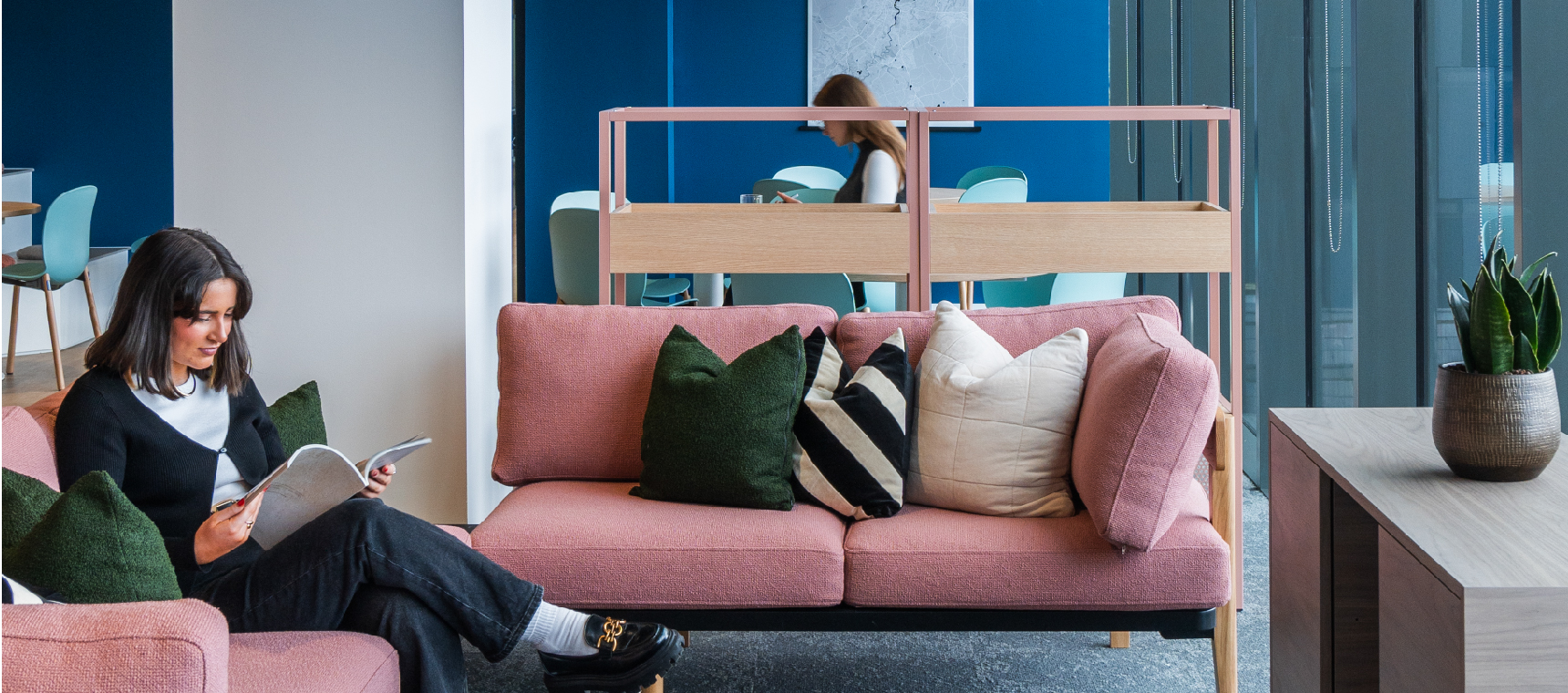 Calibro Workspace - 5 Considerations for a Hybrid Workplace. Woman sitting on a pink couch in breakout space at work.