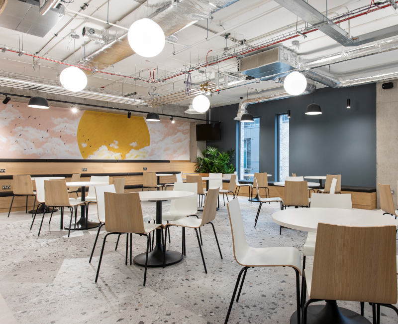 Expansive breakout space with bleachers, a mural, modern industrial ceiling and tables and chairs