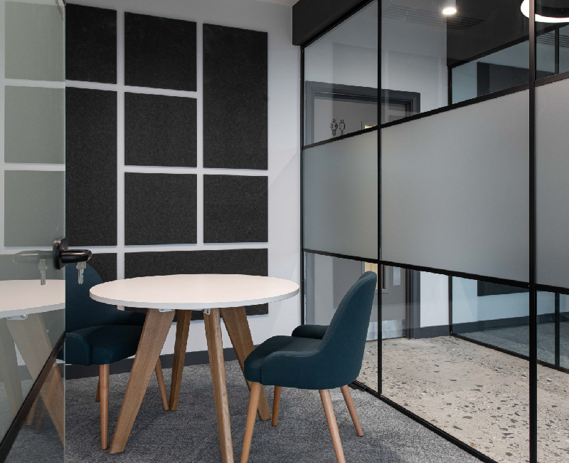 Small two person meeting room with acoustic panels on wall and crittall glass